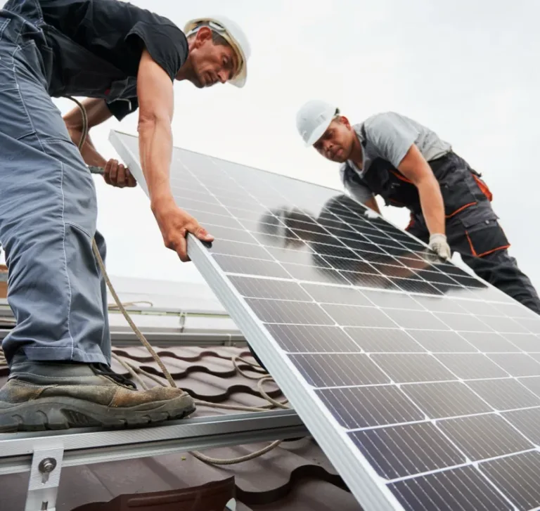 Two workers installing solar panels on a rooftop.